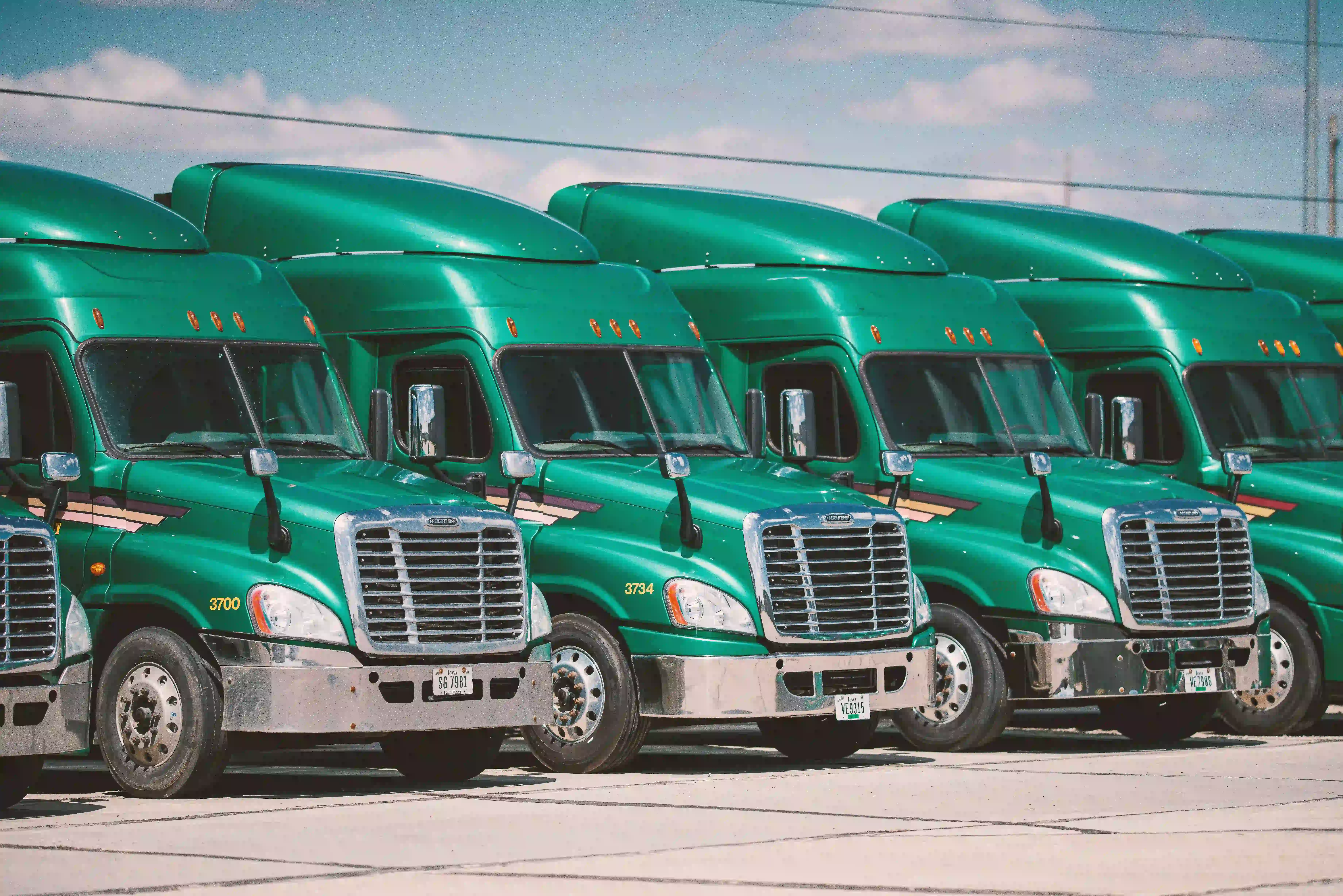 multiple green trucks parked next to eachtoher facing front at an angle