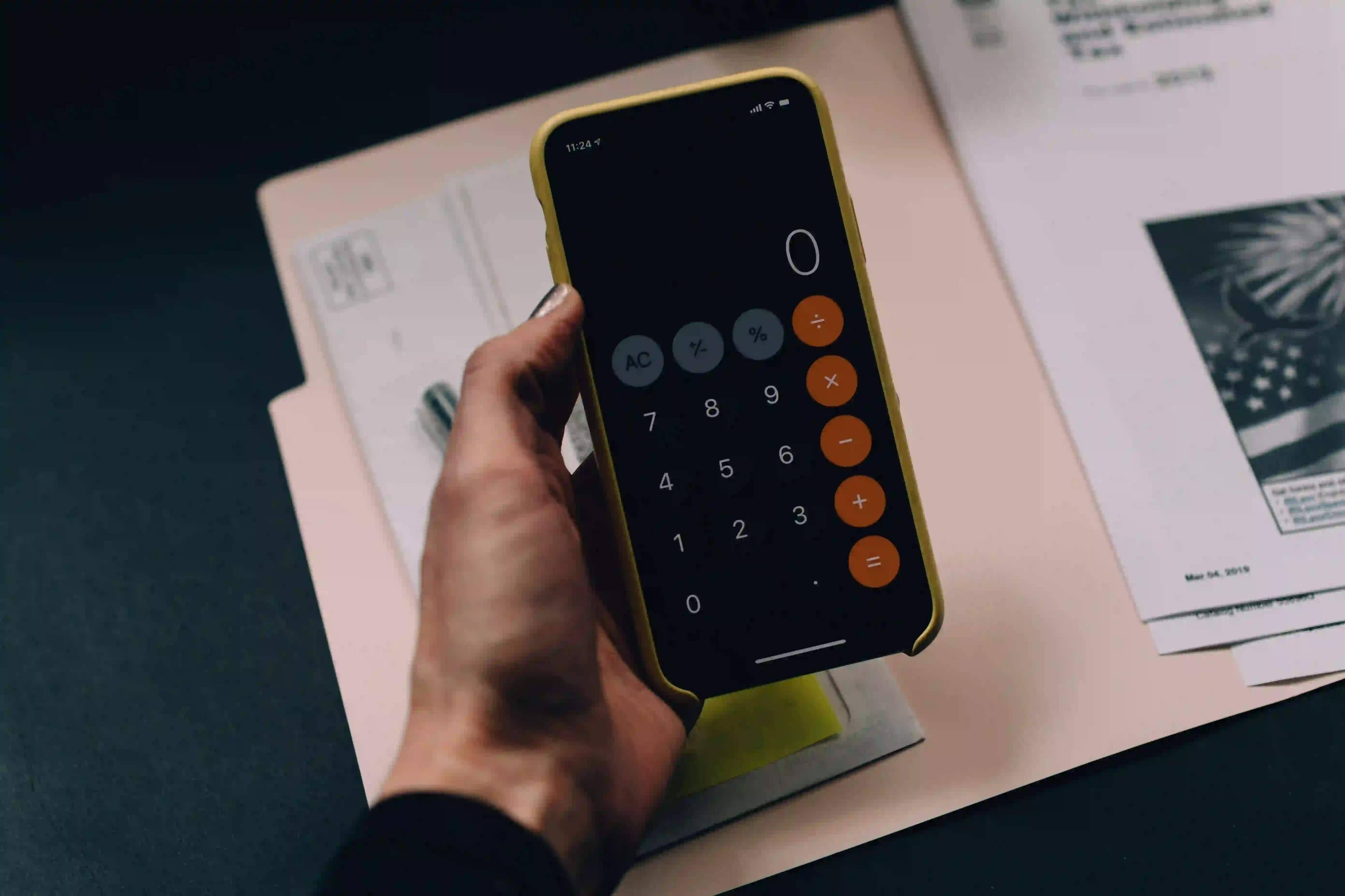 Iphone held in left hand with calculator app opened